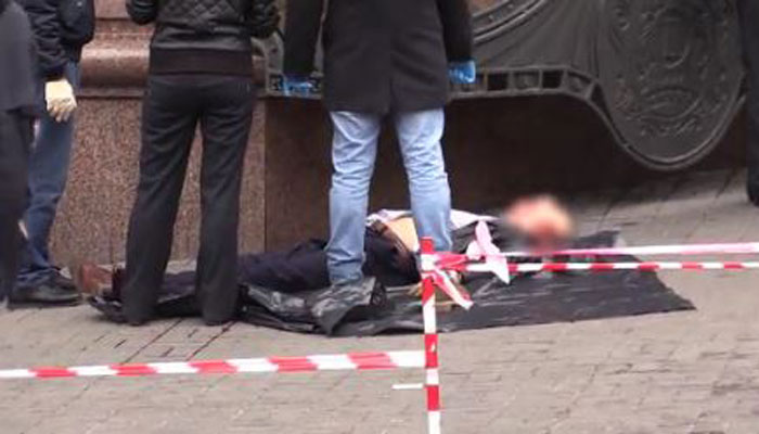 Police stand on Thursday over the bloodied body of Denis Voronenkov lying face-up on a Kiev sidewalk