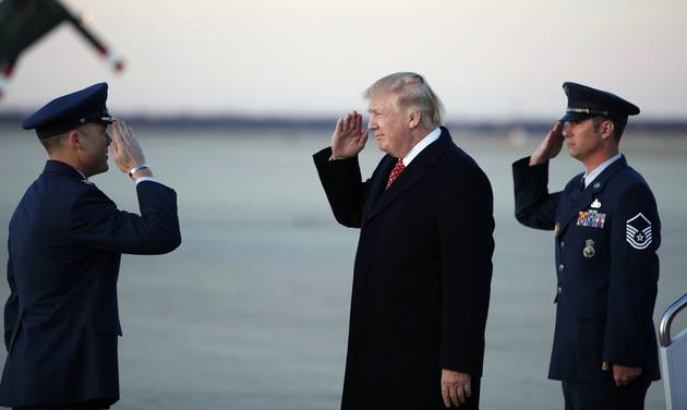 President Donald Trump salutes as he stands on the tarmac after disembarking Air Force One as he arrives Sunday