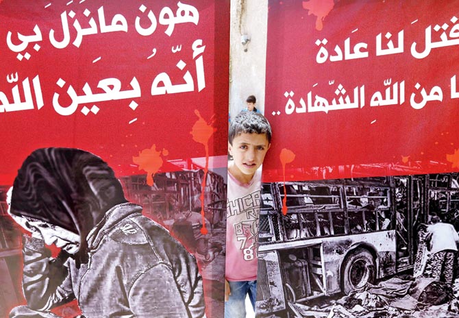 A child looks out from behind posters during a funeral in the Sayyida Zeinab mosque on the outskirts of Damascus for the victims of a bombing that targeted buses carrying evacuees