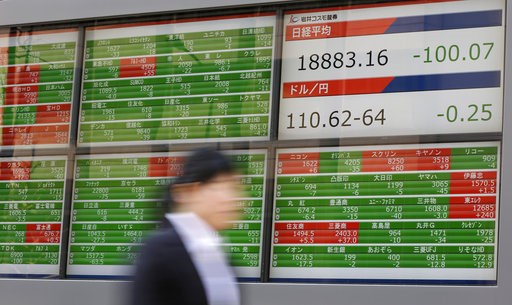 A woman walks past an electronic stock board showing Japan's Nikkei 225 index at a securities firm in Tokyo Tuesday