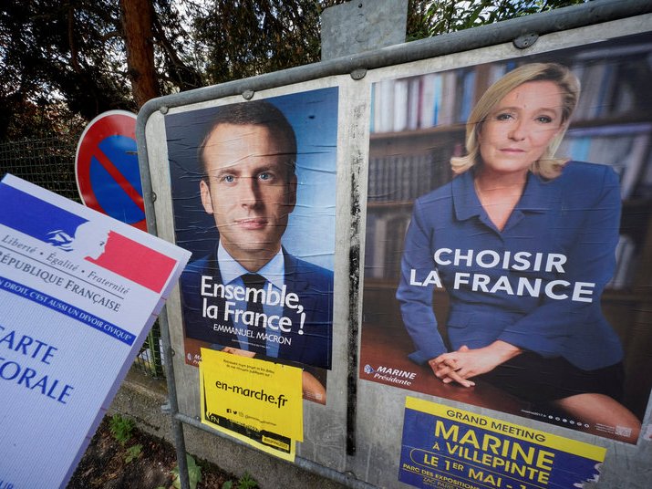 French voter's registration card near posters of the candidates in the 2017 French presidential election Emmanuel Macron head of the political movement En Marche ! or Onwards ! and Marine Le Pen French National Front