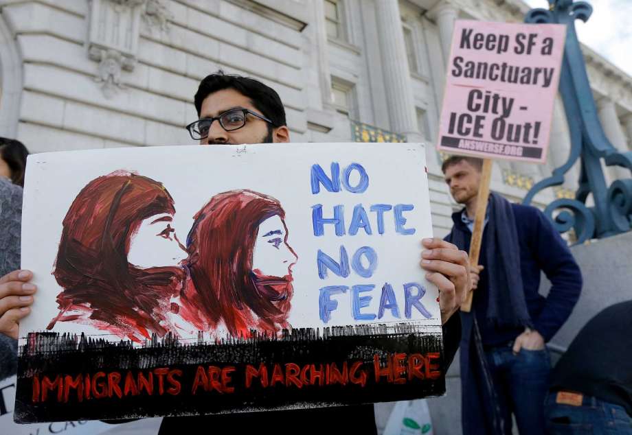 Anirvan Chatterjee left of the Alliance of South Asians Taking Action holds a sign at a rally outside of City Hall in San Francisco Wednesday Jan. 25 2017. President Donald Trump moved aggressively to tighten the nation's immigration controls Wednes