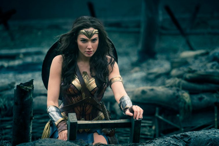 Wonder Woman climbing out of a trench with her shield strapped to her back