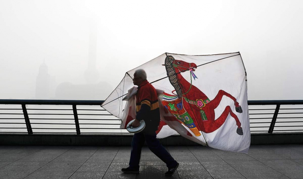 14 2016 a Chinese man carries his kite past the Pudong Financial District shrouded with fog and pollution at the Shanghai Bund in Shanghai China