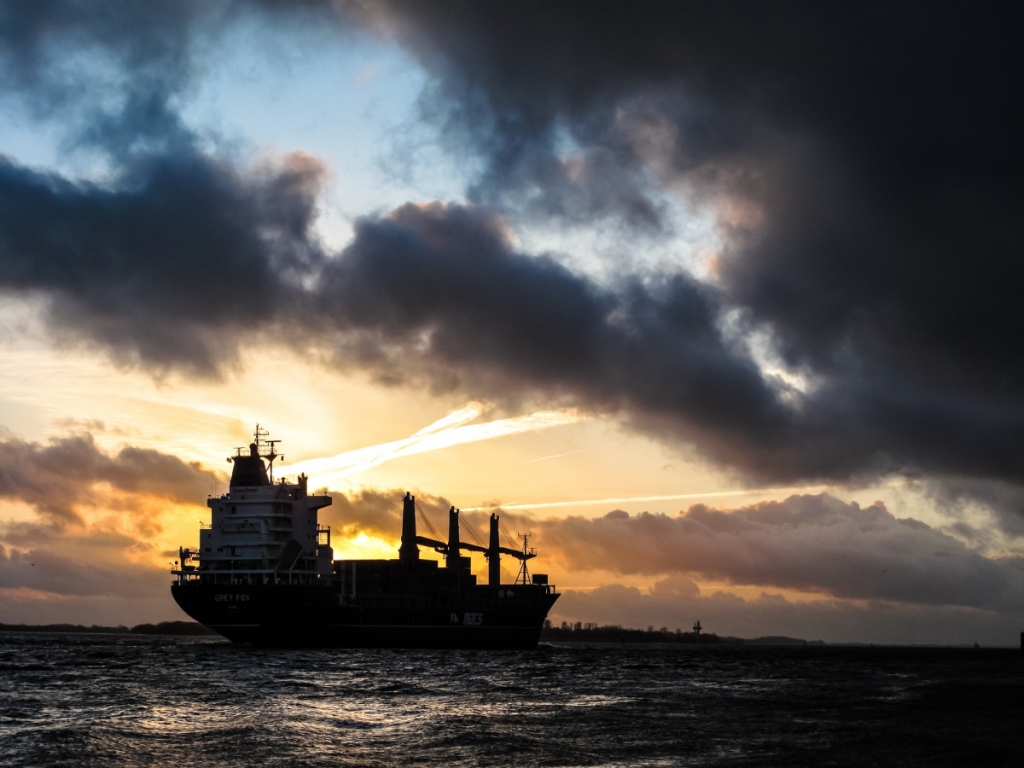 A ship sails at dusk