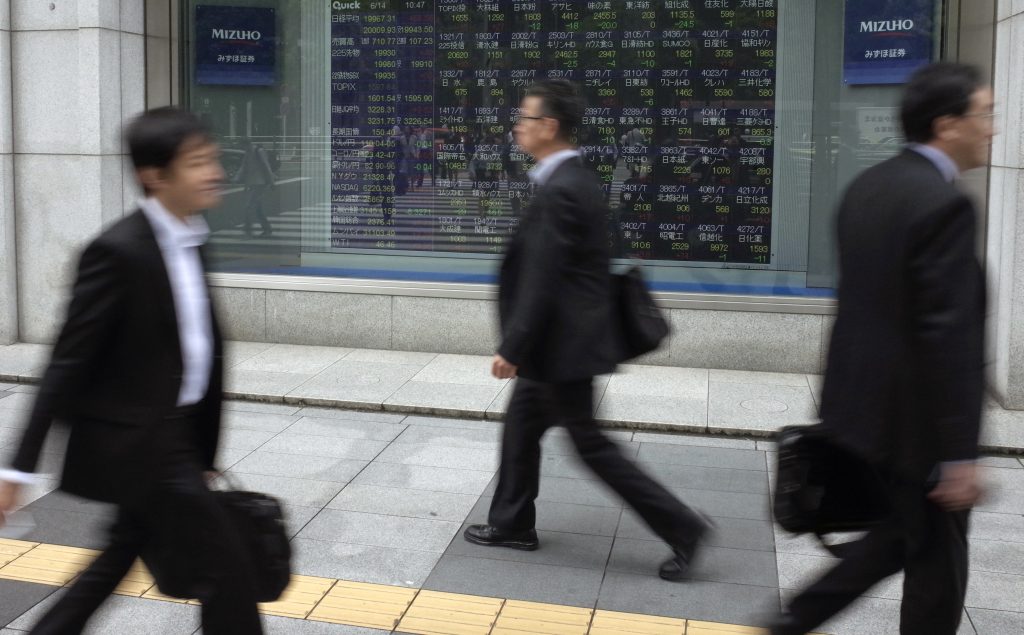 People walk past an electronic stock board showing Japan’s Nikkei 225 index at a securities firm in Tokyo Wednesday