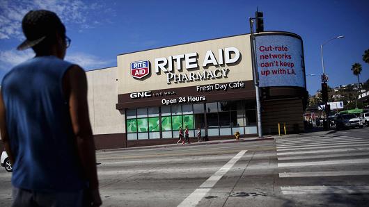 A pedestrian crosses the street in front of a Rite Aid store in Los Angeles