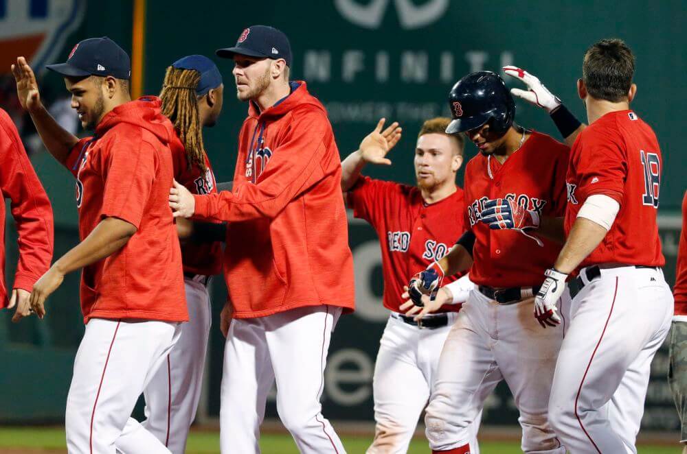 The Boston Red Sox celebrate after winning over the New York Yankees on a walk by Andrew Benintendi with bases loaded during the ninth inning of a baseball game in Boston Friday