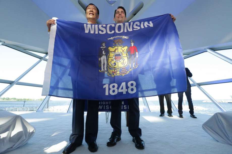 Foxconn Chairman Terry Gou left and Gov. Scott Walker hold the Wisconsin flag to celebrate their $10 billion investment to build a display panel plant in Wisconsin at the Milwaukee Art Museum in Milwaukee Wis. Thursday