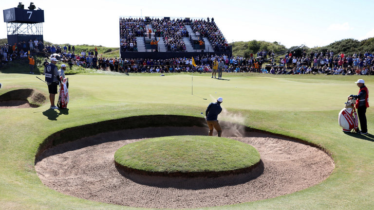 McIlroy splashes out of a bunker on the seventh hole