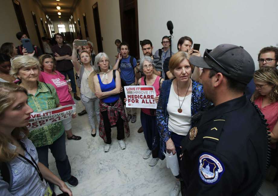 Protesters against the Republican health care bill talk to US. Capitol Police officer near the office of Senate Majority Leader Mitch Mc Connell of Ky. Monday