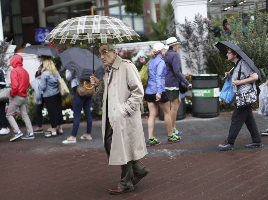 Don Kregsman center walks through the grounds of the Billie Jean King National Tennis Center during a rain delay in the first round of the U.S. Open tennis tournament Tuesday Aug. 29 2017 in New York