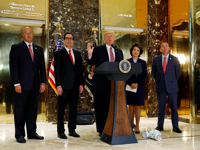 U.S. President Donald Trump is flanked by Director of the National Economic Council Gary Cohn Treasury Secretary Steven Mnuchin Secretary of Transportation Elaine Chao and Director of the Office of Management and Budget Mick Mulvaney as he speaks