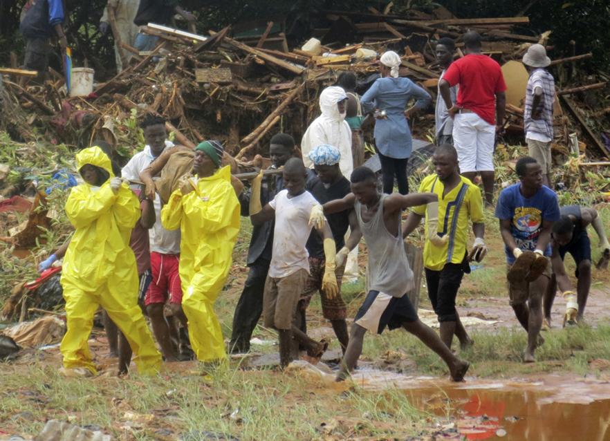 Rescue workers carry the body of a victim from the site of a mudslide in Regent east of Freetown Sierra Leone Monday Aug. 14 2017. Mudslides and torrential flooding has killed many people in and around Sierra Leone's capital early Monday following