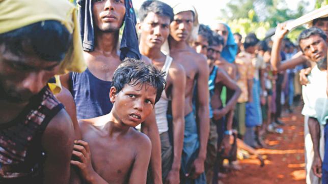 A Rohingya refugee boy looks on as he stands in a queue to receive relief supplies given by local people in Cox's Bazar yesterday