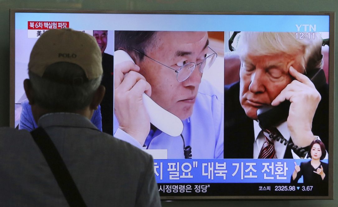 A man watches a television screen showing U.S. President Donald Trump right and South Korean President Moon Jae-in during a news program at the Seoul Railway Station in Seoul South Korea on Tuesday. The signs read'Need sanctions on North Korea