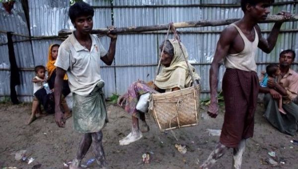 Rohingya men carry their sick mother in the streets as they arrive at Bangladesh border at Teknaf Bangladesh