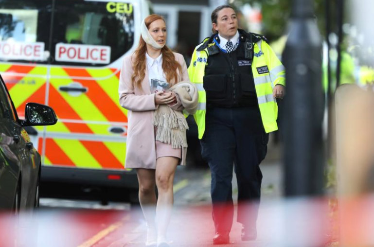 An injured woman is led away following a blast caused by an improvised explosive device on a London Underground train Sept. 15. The blast injured more than a dozen people and is being treated as terrorism by police investigators. (CNS