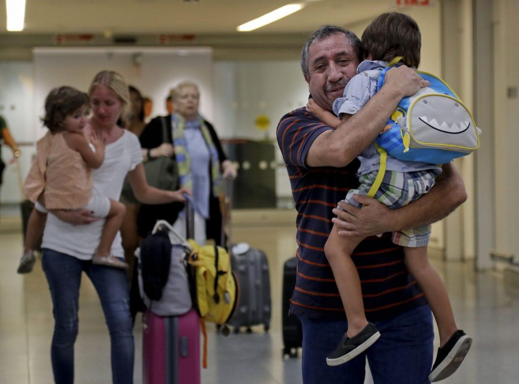 Juan Rojas right of Queens hugs his 4-year-old grandson Elias Rojas as his daughter-in-law Cori Rojas left carries her daughter Lilly 3 through the terminal at JFK airport after Cori arrived on a flight from San Juan Puerto Rico Tuesday Sept. 2