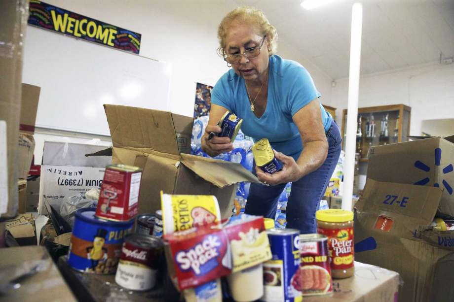 Irma Decker marks out scan codes as she packs boxes with canned ggods while parishioners at the Gethsemane Lutheran Church pack boxes of relief supplies