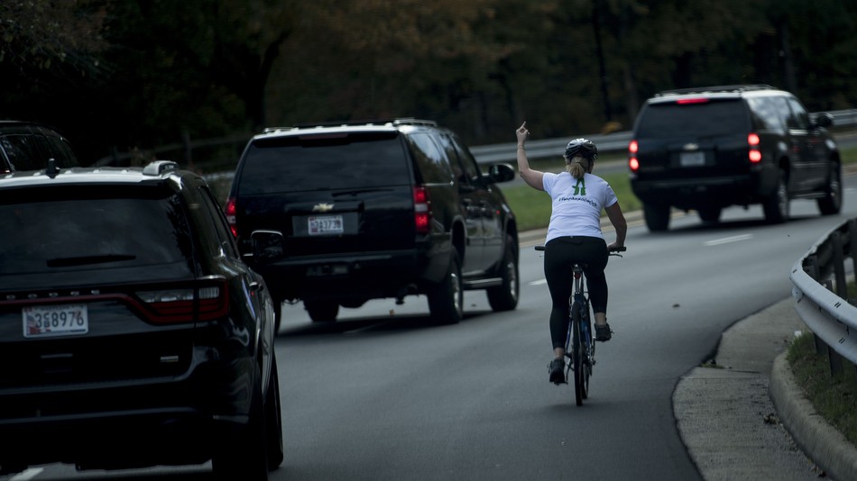 Juli Briskman gestures with her middle finger as a motorcade with U.S. President Donald Trump departs Trump National Golf Course in Sterling Virginia on Oct. 28