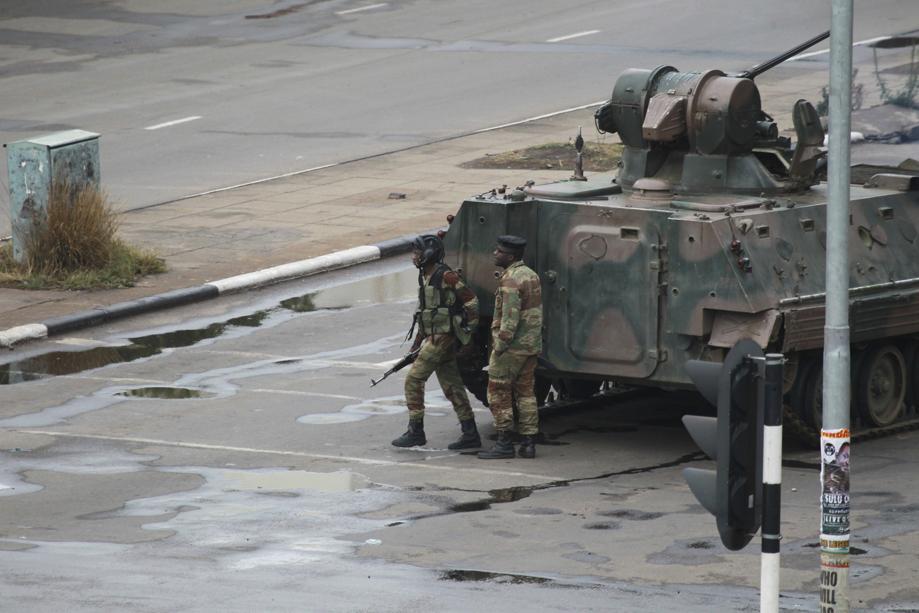 A military tank is seen with armed soldiers on the road leading to President Robert Mugabe's office in Harare Zimbabwe Wednesday Nov. 15 2017. Overnight at least three explosions were heard in the capital Harare and military vehicles were seen in