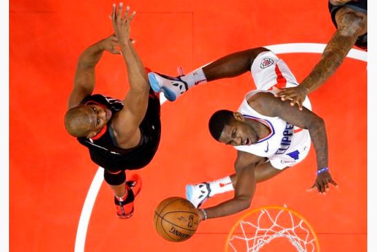 Los Angeles Clippers guard Jawun Evans right shoots as Houston Rockets guard Chris Paul defends during the first half of an NBA basketball game Monday Jan. 15 2018 in Los Angeles