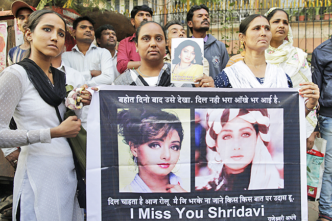 Fans of Bollywood actress Sridevi hold posters as they wait outside her residence to pay their last respects in Mumbai India yesterday. – AP