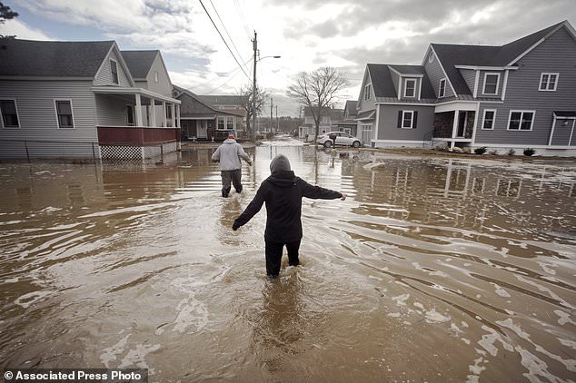 Kaylee Collin right and Spencer Stone walk through water along North Avenue in Camp Ellis in Saco Maine on Sunday