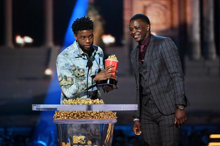 Actor Chadwick Boseman, winner of the Best Hero award for 'Black Panther,&#039 presents his trophy to James Shaw Jr. onstage during the 2018 MTV Movie And TV Awards at Barker Hangar