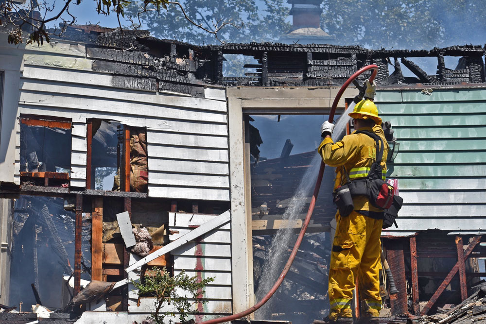 Firefighter hoses a burned house