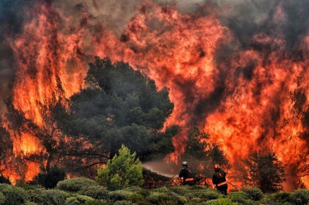 Firefighters try to extinguish flames from a wildfire at the village of Kineta near Athens on Tuesday