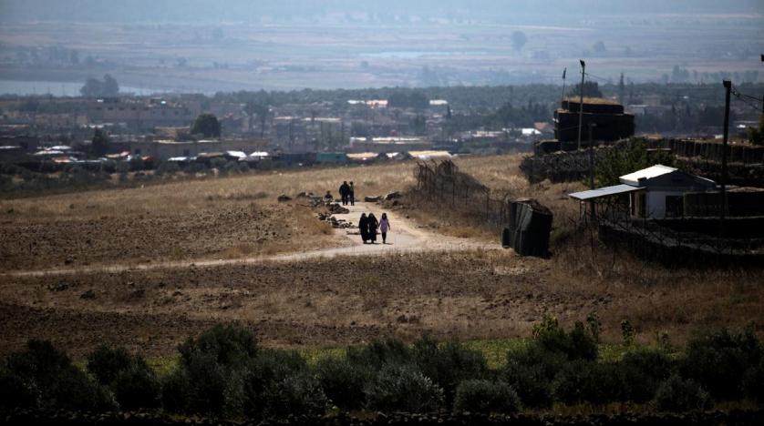 People walk near the Israel Syria border line as it is seen from the Israeli-occupied Golan Heights Israel