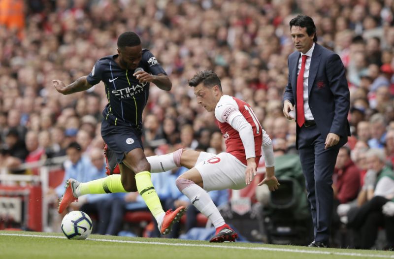 Arsenal manager Unai Emery right watches Manchester City's Raheem Sterling left fight for the ball with Arsenal's Mesut Ozil during the English Premier League soccer match between Arsenal and Manchester City at the Emirates stadium in London