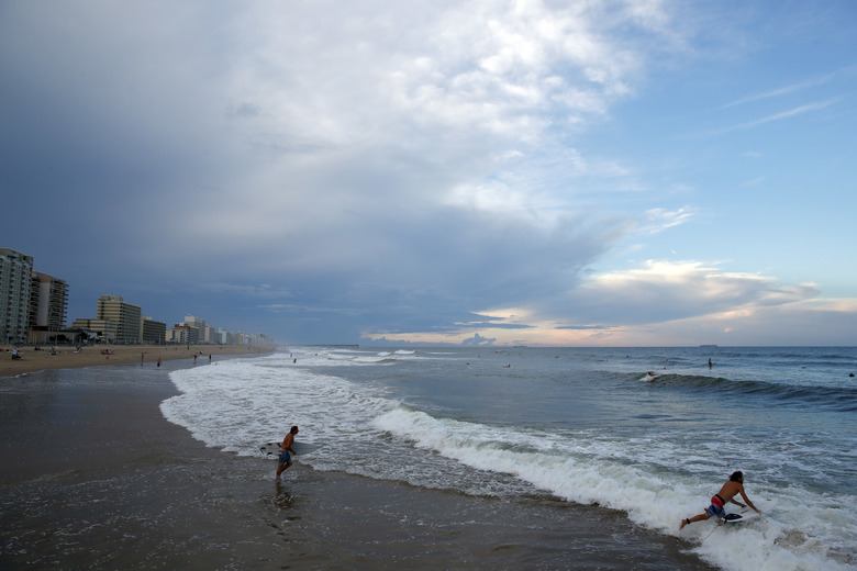 Surfers head to the waves Tuesday Sept. 11 2018 in Virginia Beach Va. before the arrival of Hurricane Florence