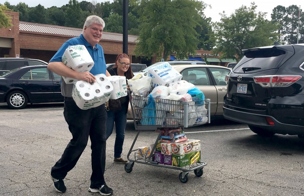 Food Lion employee Greg Partin helps a customer to her car on Monday Sept. 10 2018 at the Woodcroft shopping center in Durham N.C. Residents of eastern and central North Carolina are stripping grocery shelves and emptying supplies of gasoline as Hurric