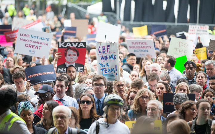 Activists hold signs at a rally calling on Sen. Jeff Flake to reject Judge Brett Kavanaugh's nomination to the Supreme Court