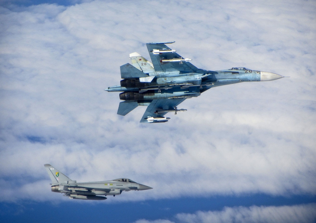 A Russian SU-27 Flanker aircraft banks away with a RAF Typhoon in the background from June 2014