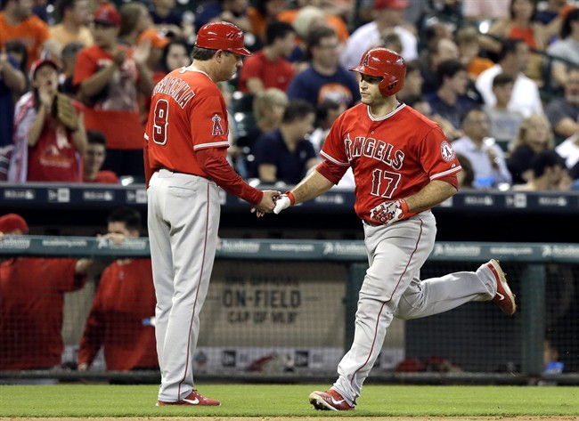 Los Angeles Angels third base coach Gary Di Sarcina congratulates Chris Iannetta as he rounds the bases on a solo homer against the Houston Astros in the third inning of a baseball game Tuesday