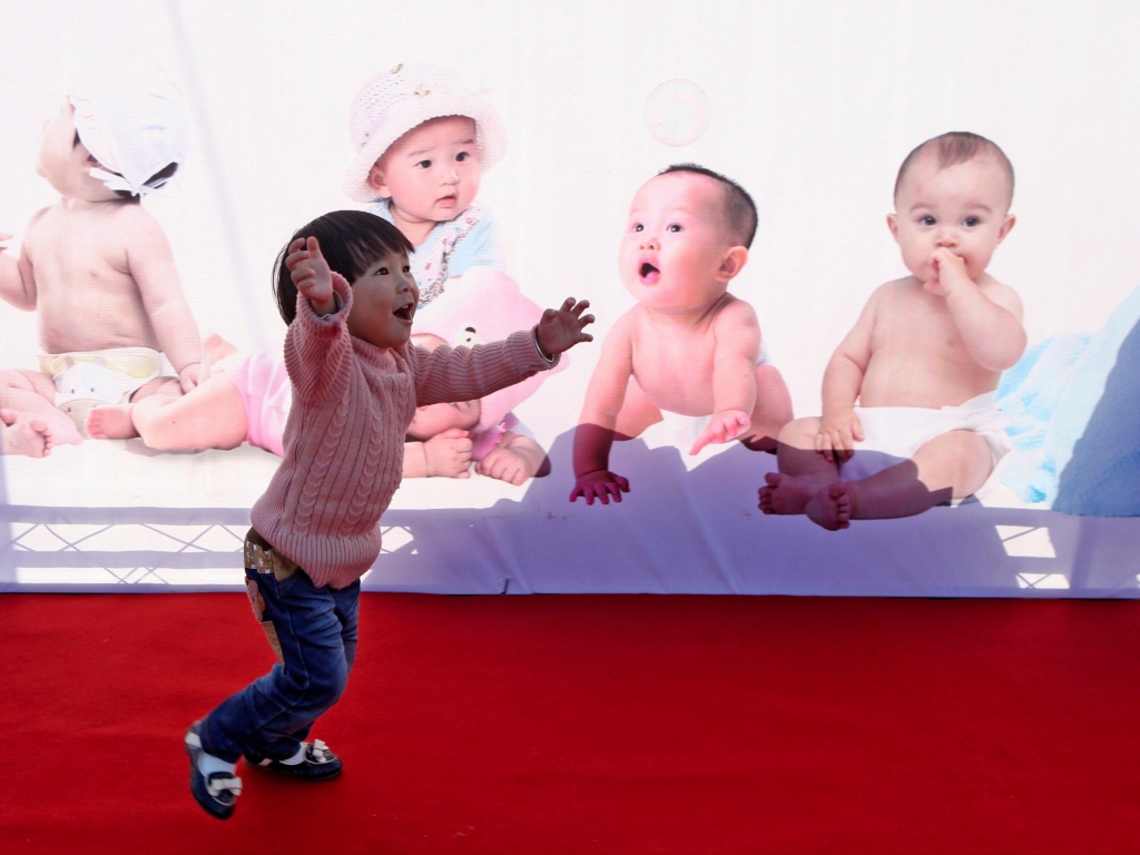 China Daily China Daily Information Corp  ReutersA girl runs in front of an advertising board in Taizhou