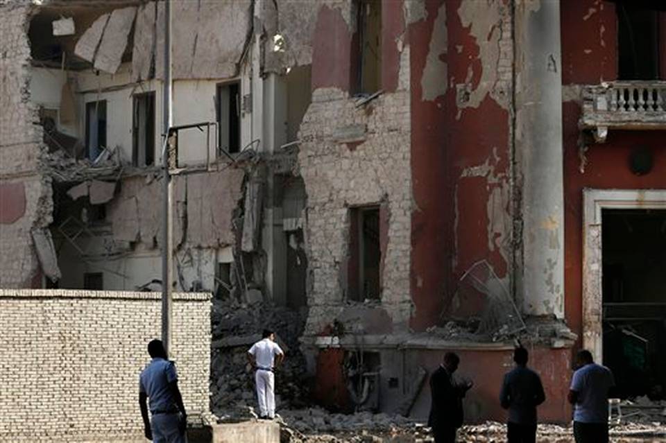 Egyptian policemen stand at the base of the crumbled facade of the Italian consulate following a blast that killed at least one person in Cairo Egypt Saturday