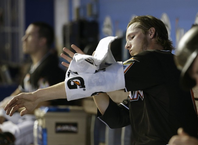 Miami Marlins starting pitcher Adam Conley wraps his arm in a towel after pitching in the first inning of a baseball game against the Cincinnati Reds Saturday