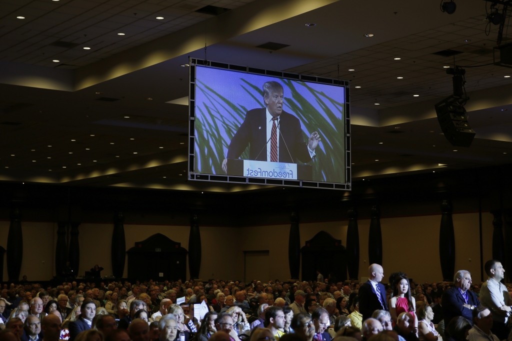 Donald Trump is seen on a screen as he speaks