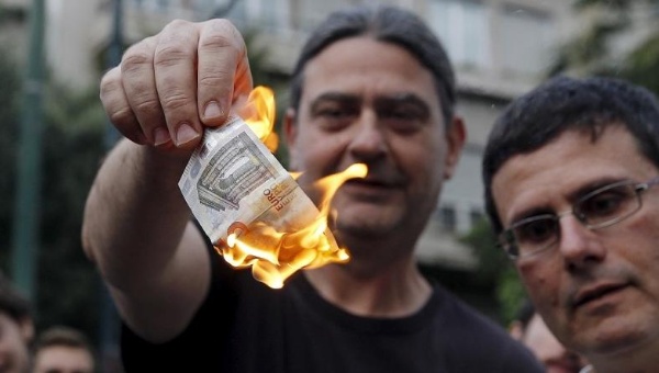 Anti-austerity protesters burn a euro note during a demonstration outside the European Union offices in Athens Greece