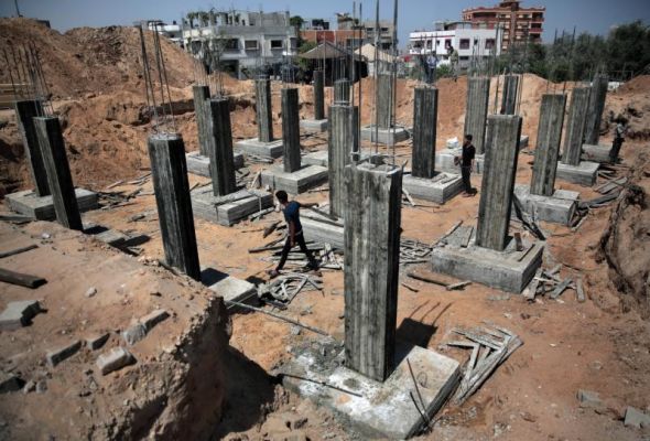 Palestinian workers rebuild a house which was destroyed