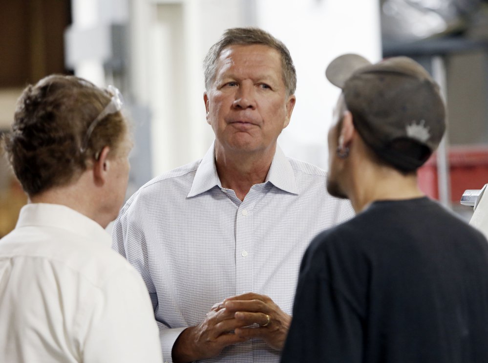 Ohio Gov. John Kasich talks with Joshua Bowman right and Joe Shean during a visit at RP Abrasives in Rochester N.H