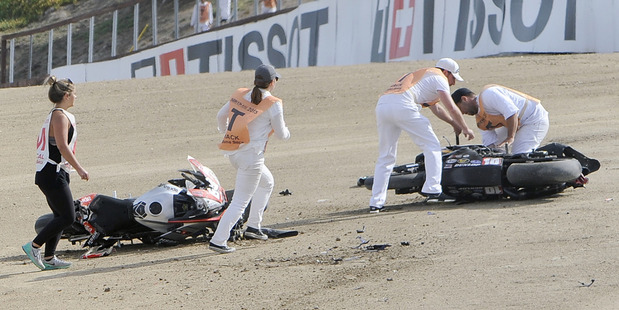 Medical and track personnel attend to bikes following a chain reaction crash on the first lap of a World Superbike race at Mazda Raceway