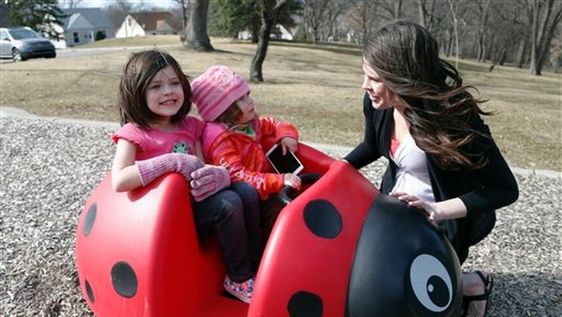 Michelle Halonen enjoying the warm day with daughters Madilyn left and Ellie at a park in St. Louis Park Minn.| AP