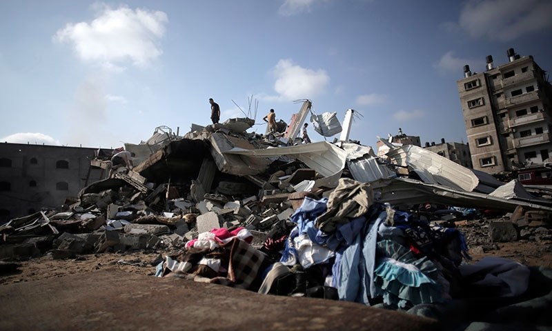 Palestinians inspecting the damage to their house after it was destroyed in an Israeli air strike during last summer's conflict. ─ AP  File