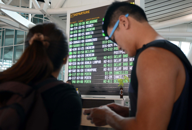 Passengers check flight information in the international terminal at Bali's Ngurah Rai airport in Denpasar